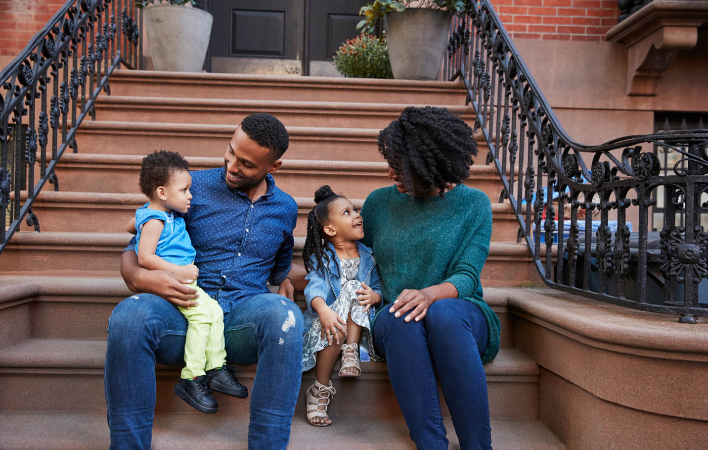 A family sitting on the steps of their city home - get peace of mind when you work with Rest Easy Pest Control Suffolk County.