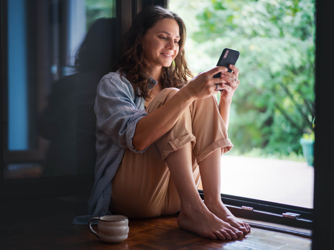 A woman sitting next to her window - contact Rest Easy Pest Control today for wildlife removal in Suffolk County, NY and experience peace of mind.